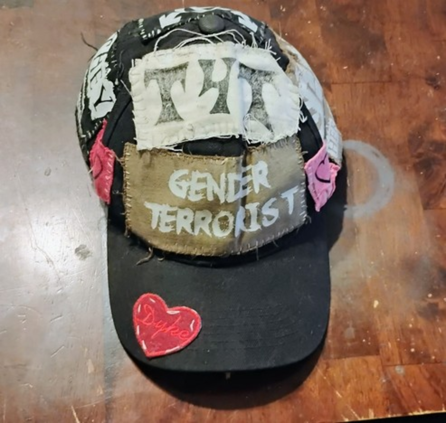 front of my gender terrorist hat featuring t4t and gender terrorist and dyke heart patches