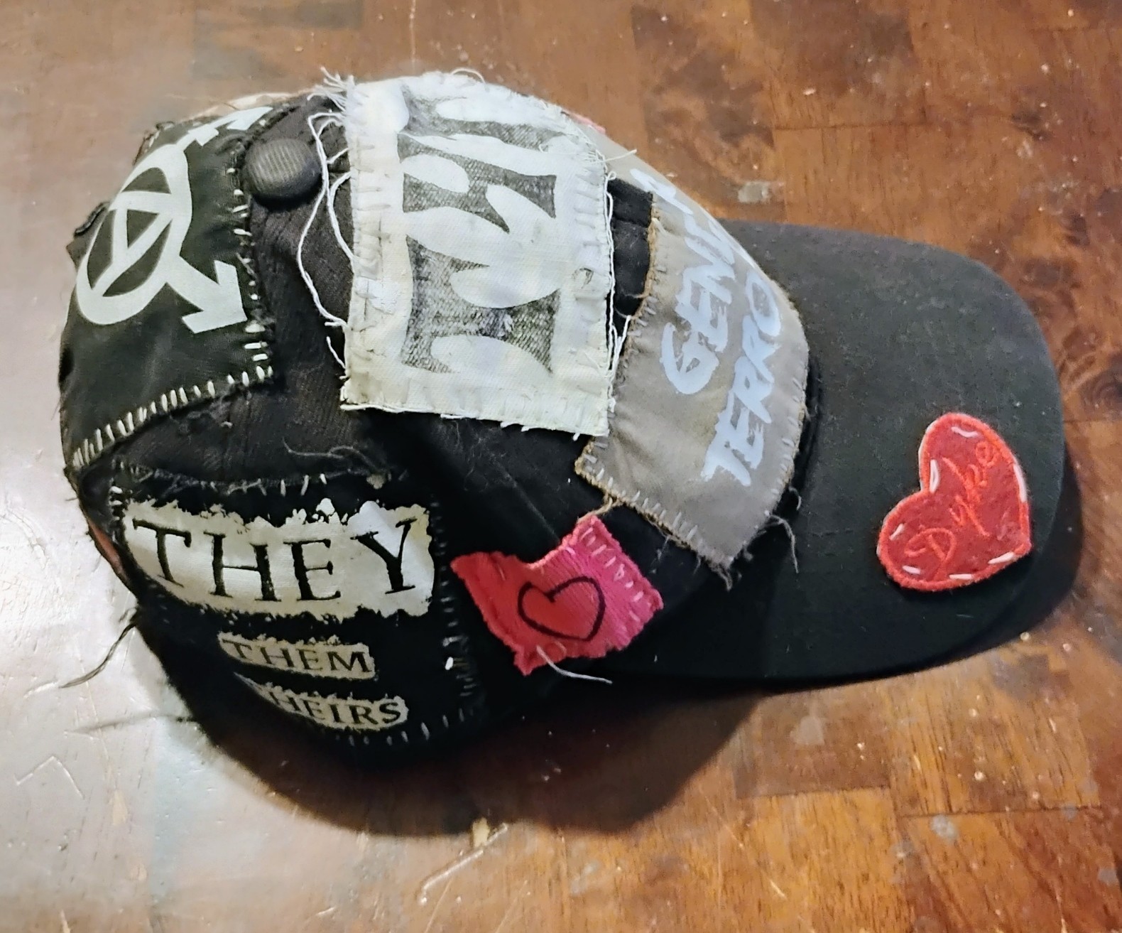 side of my gender terrorist hat with they/them pronoun and pink heart patch